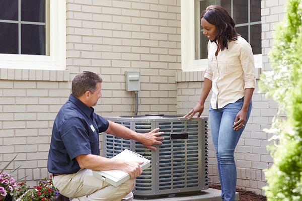 Air conditioner technician consulting with a customer by her AC system