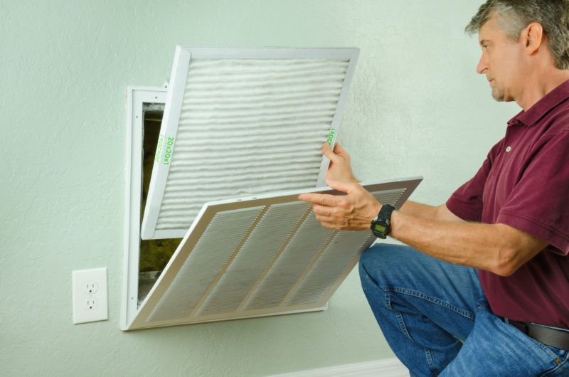 Man replacing air filter in AC unit for indoor allergies