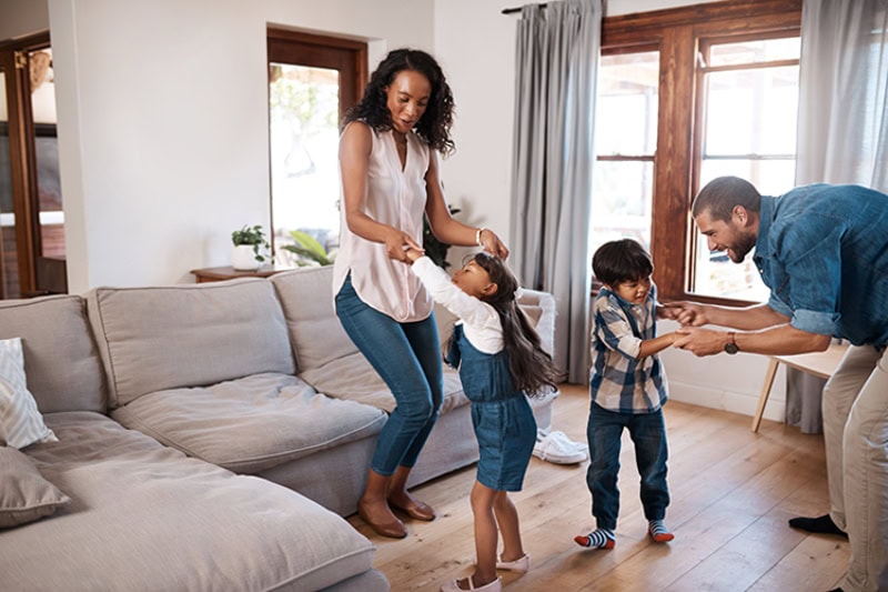 Family dancing in living room together.