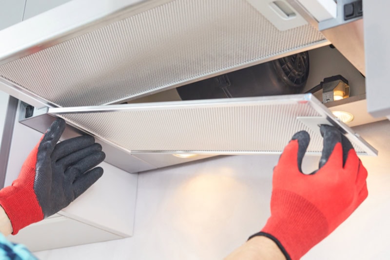 Should You Close Your HVAC Vents? Photo of a person with red gloves taking down a vent cover.